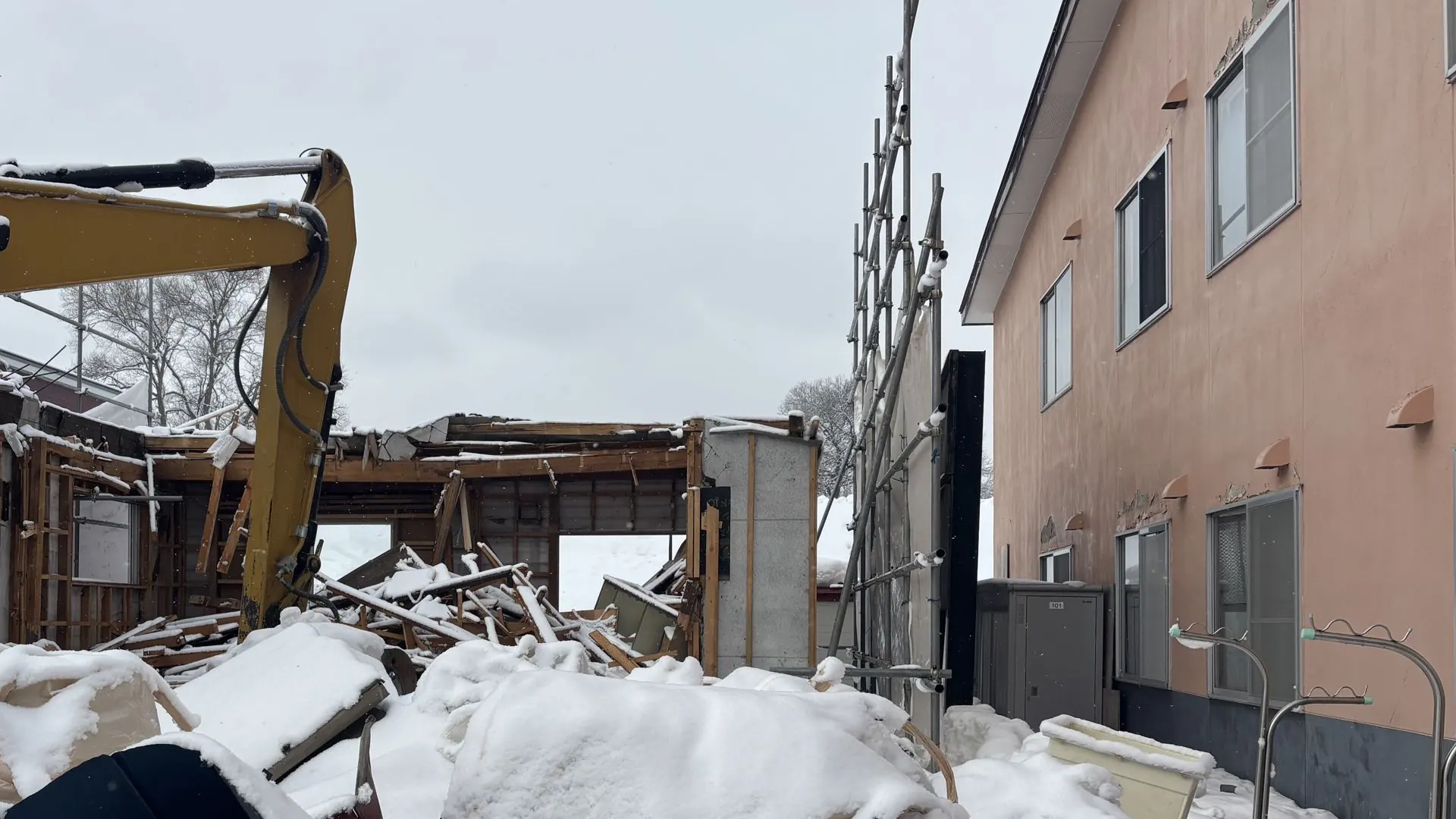 冬の解体現場。重機が木造の建物を取り壊している